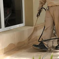 General pest control technician spraying exterior perimeter around a home in Miami, FL