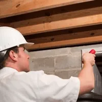Termite inspection technician checking a basement wall and framing for termite activity in Miami, FL