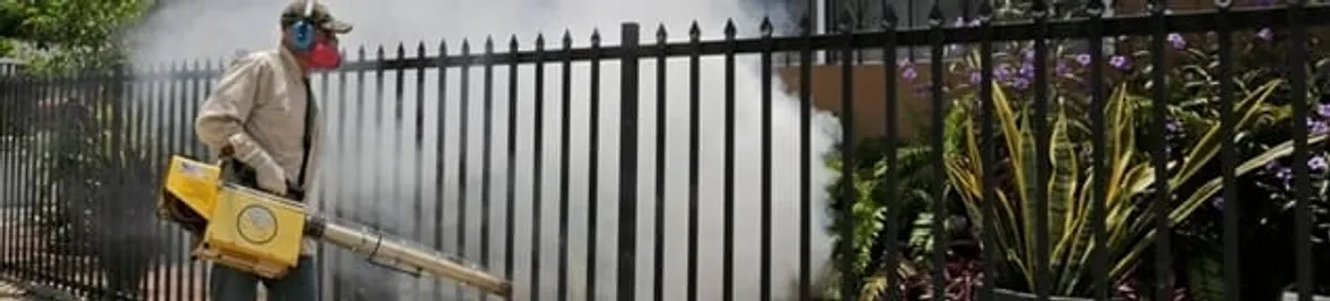 Mosquito control technician fogging a yard perimeter for mosquito reduction in Miami, FL